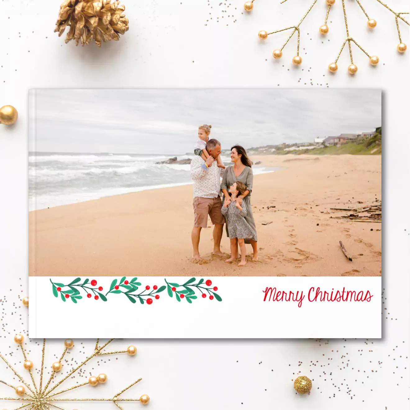 Christmas-themed photobook cover featuring a family walking on a beach. The design includes festive holly decorations and the text 'Merry Christmas' in red on a white background.