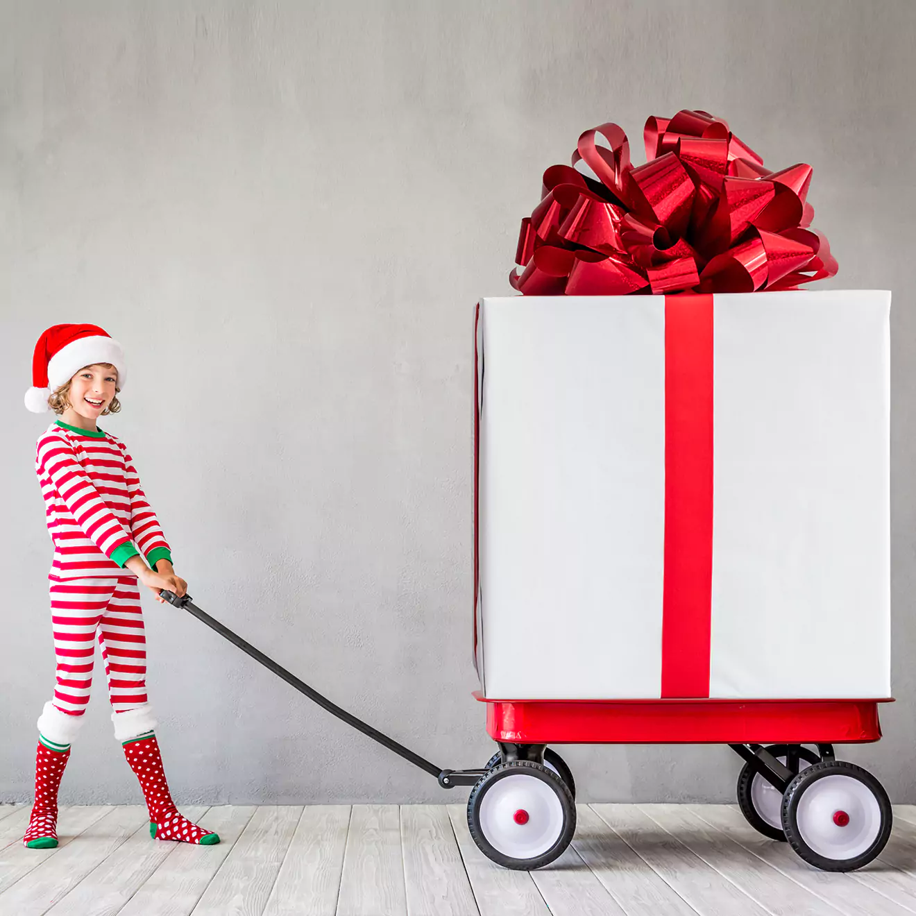 A cute little girl pulling a cart with a present on it, featured next to our Christmas cut-off times. This charming image adds a festive touch to our holiday page, reminding you of important deadlines.