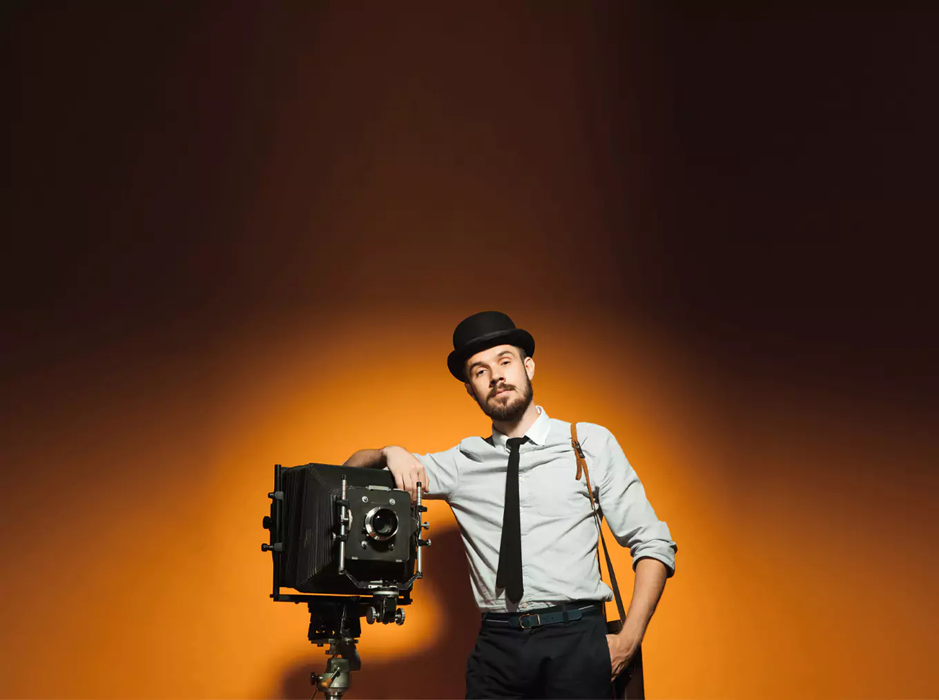 "Promotional image for professional photographers featuring a man in vintage attire with a large format camera. The text reads 'Are you a professional photographer? Join us!' against a gradient orange background."