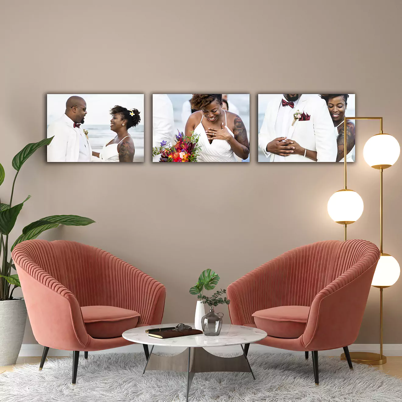 Modern living room featuring a set of three framed wedding photos on a beige wall. The photos depict a couple on their wedding day. The room includes two coral-coloured armchairs, a small round white table, a potted plant, and a stylish floor lamp with three spherical lights. Ideal for personalised gifts in South Africa.