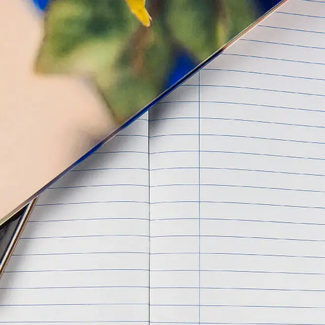 Close-up image of an open hardcover notebook with graph paper pages. The notebook features a sturdy binding and is laid flat on a wooden surface. Ideal for note-taking, journaling, or sketching, this notebook is a practical and thoughtful gift idea for various occasions.