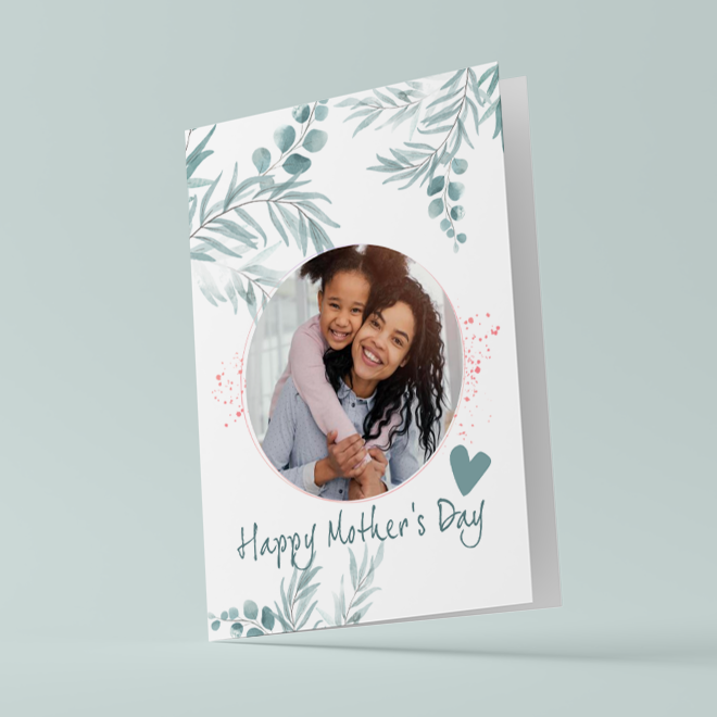 Mother''s Day greeting card featuring a circular photo of a smiling woman and child. The card is adorned with blue gum leaf illustrations and a heart design. The text ''Happy Mother''s Day'' is written in elegant script at the bottom. Ideal for personalised gifts in South Africa.