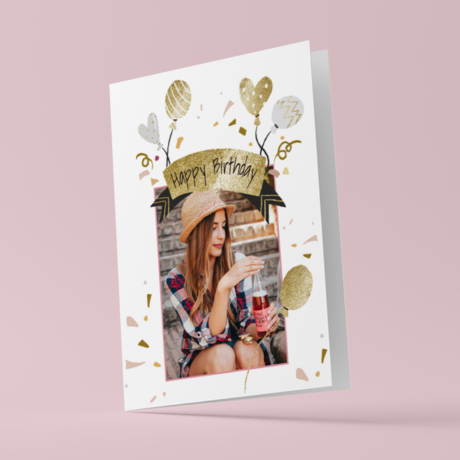 Happy Birthday card featuring a young woman in a plaid shirt and hat, holding a drink. The card has a festive design with gold and silver balloons, confetti, and a ''Happy Birthday'' banner. Ideal for personalised gifts in South Africa, perfect for birthdays and celebrations.