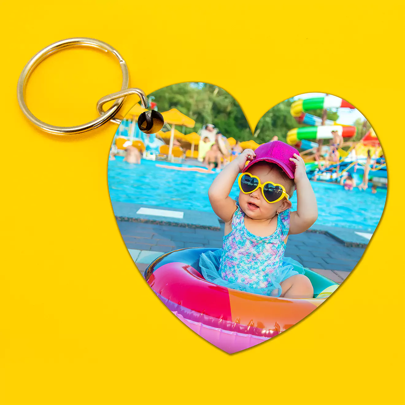 Heart-shaped personalised keyring featuring a photo of a child wearing sunglasses and a hat, sitting in a pool float. The keyring has a metal ring and clasp, and the background is bright yellow. Ideal for gifts for her, baby shower gift ideas, and personalised gifts in South Africa.