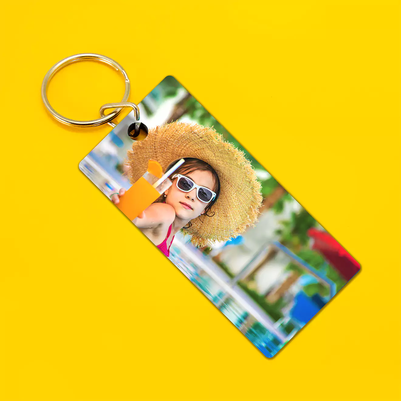 Rectangular personalised keyring featuring a vibrant photo of a child wearing a straw hat and sunglasses, holding a drink by the poolside. The keyring has a metal ring attached and is set against a bright yellow background. Ideal for gifts for men, women, and special occasions.