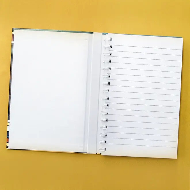 Open hardcover notebook with a spiral binding, featuring one blank page and one lined page, displayed on a yellow background. Ideal for note-taking, journaling, or as a personalised gift. Suitable for various occasions such as birthdays, Christmas, or Valentine's Day.