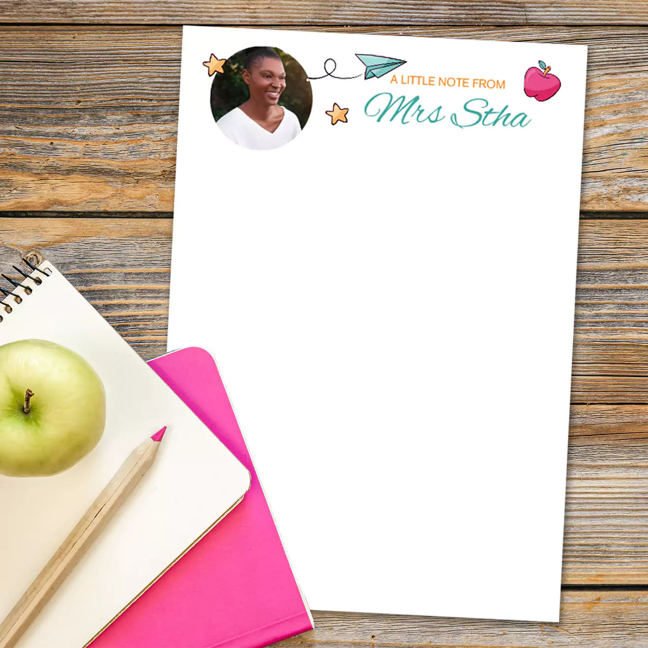 "Personalised teacher notes stationery featuring a photo and the text 'A little note from Mrs. Stha' with a paper airplane and apple illustration. The notepad is placed on a wooden surface alongside a green apple, a pencil, and a pink notebook. Ideal for teacher gifts and personalised stationery."