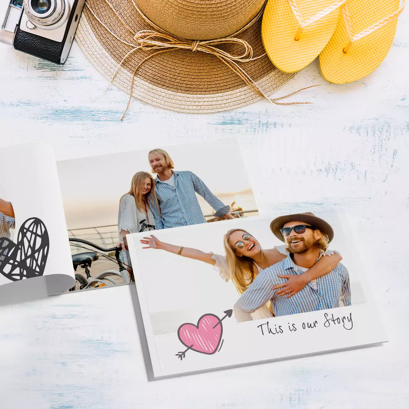 Open photobook on a white wooden surface, featuring a couple enjoying a sunny day. The cover reads ''This is our Story'' with a pink heart and arrow illustration. Nearby are a straw hat, yellow flip-flops, and a vintage camera, suggesting a travel or summer theme. Ideal for personalised gifts in South Africa, photo albums, and Valentine''s Day gift ideas.