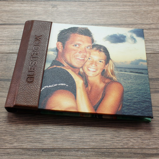 Personalised guestbook with a brown leather spine and a custom photo cover featuring a smiling couple by the sea. Ideal for weddings, baby showers, or as a thoughtful gift for special occasions.