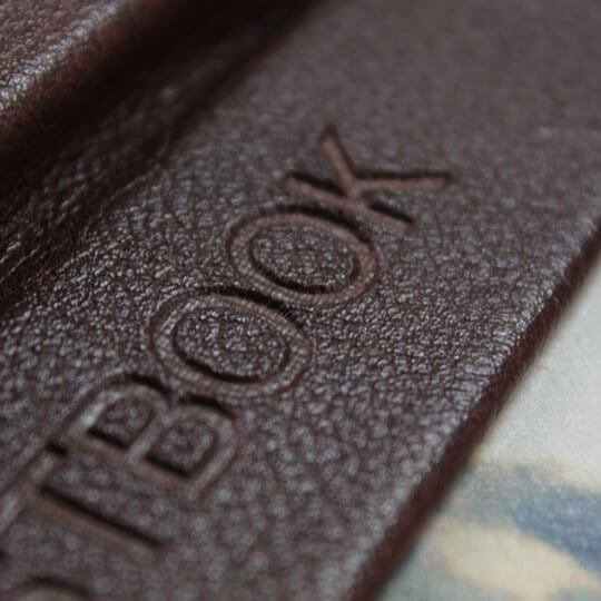 Close-up of a brown leather photo book cover with the word "PHOTOBOOK" embossed on it. Ideal for personalised gifts in South Africa, including Christmas gifts, baby shower gift ideas, and gifts for men.