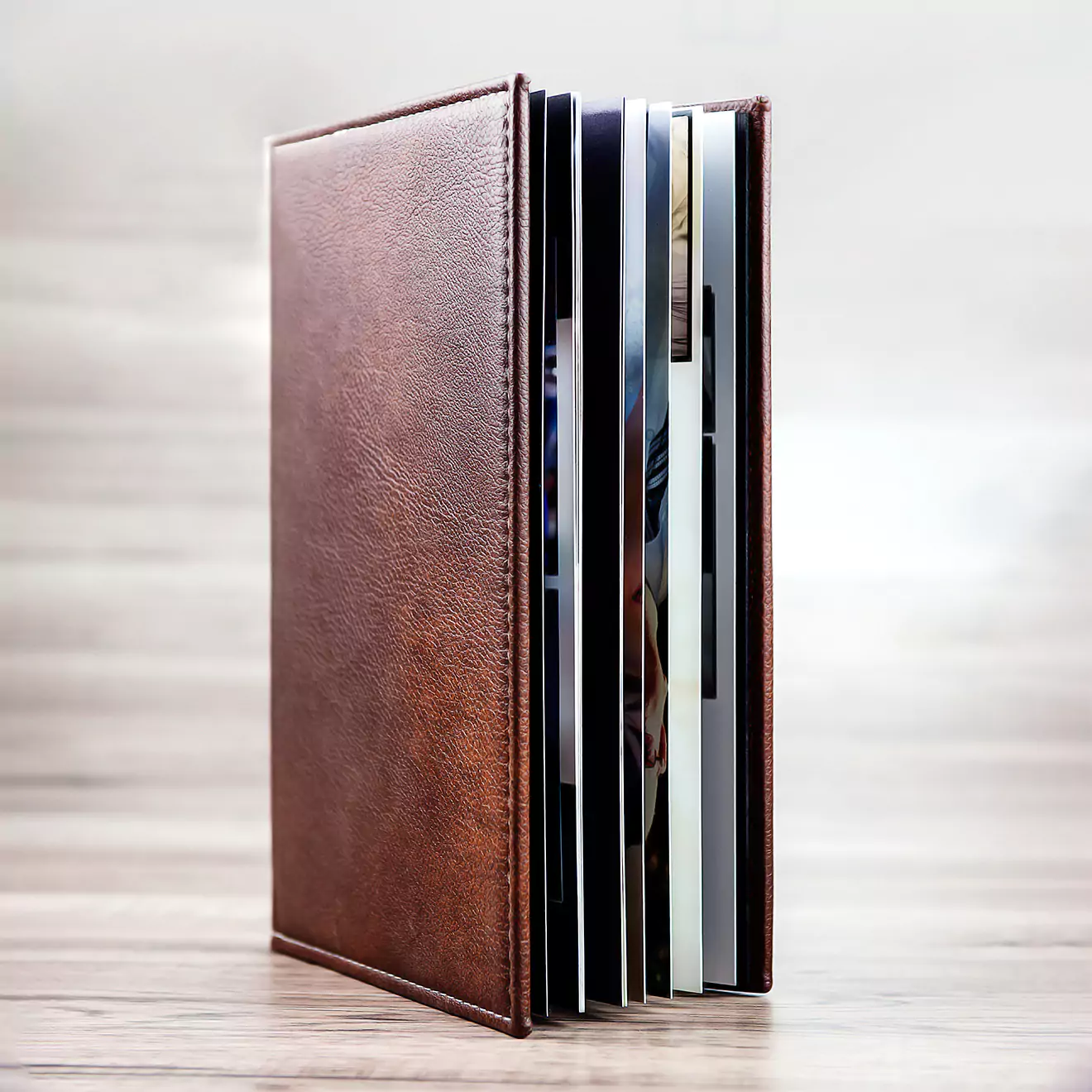 Elegant brown leather photo album standing upright on a wooden surface, showcasing its high-quality binding and multiple pages. Ideal for preserving cherished memories, this photo album makes a perfect gift for special occasions such as Christmas, birthdays, or baby showers.